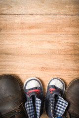 Daddy's boots and baby's sneakers, on wood background, fathers d