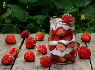 strawberries and cream in a jar on a wooden background