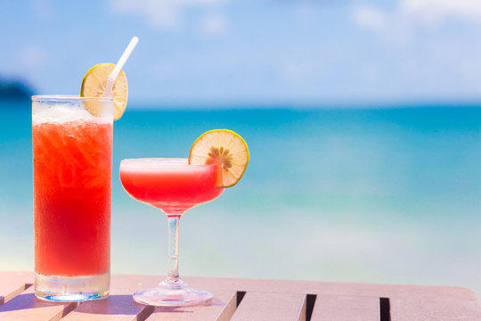 two  exotic cocktails on wooden table by the sea
