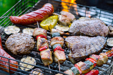 meat and vegetables cooking on grill with flames