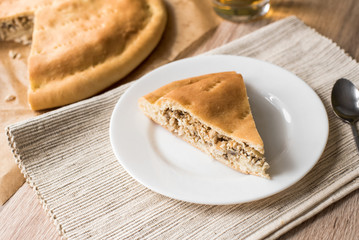 Pie with chicken, eggs and mushrooms on a white plate