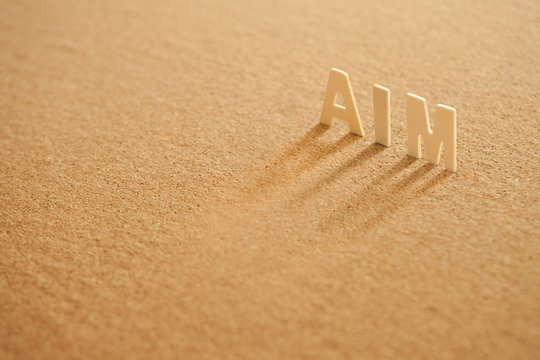 Aim word made of wood with shadow on compressed board