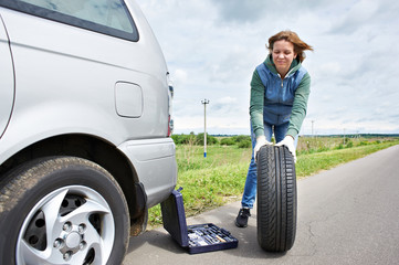 Fototapeta na wymiar Woman changing wheel of car