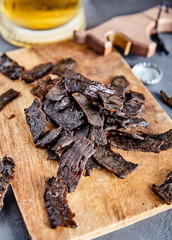 Beef jerky on wood board and beer
