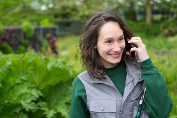 Young attractive woman working in a public garden using mobile