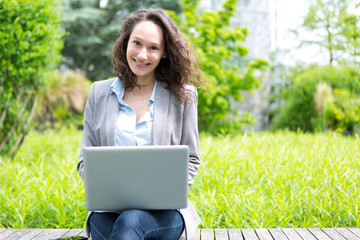 Young attractive business woman working at the park during a pau