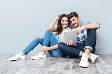 Couple using tablet sitting on the floor at home