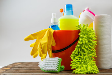 Bucket with cleaning items on light background