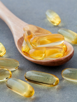 Close up capsules fish oil in wooden spoon .The supplement high