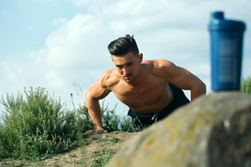 muscular man training near water bottle