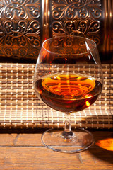 Glass of cognac with lemon on wooden background