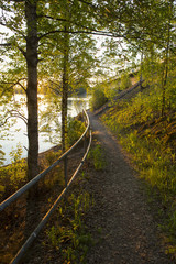 A path is going next to a lake. Image taken during sunset in Finland.