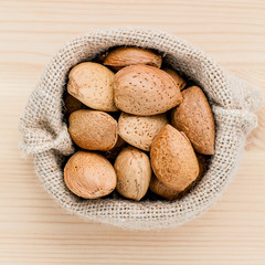 Almonds kernels and whole almonds on wooden background. Whole an