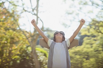 Excited boy standing in park with arms raised