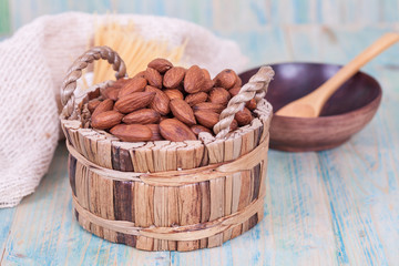 Almonds in brown bowl on textured wooden background