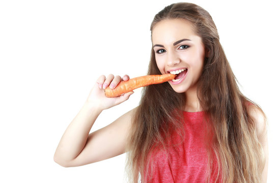 Happy young woman eating a carrot (isolated on white)