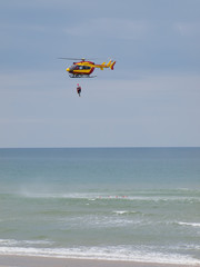 A red and yellow helicopter with rescuers