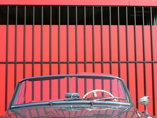 Wertvolles Cabriolet der Fünfziger Jahre mit elfenbeinfarbenem Lenkrad vor einem roten...