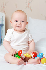 Cute smiling baby laughing and smiling with a toy in his hand. L