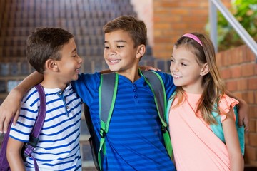 Smiling school kids standing with arm around