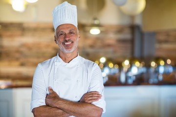 Portrait of smiling chef standing with arms crossed