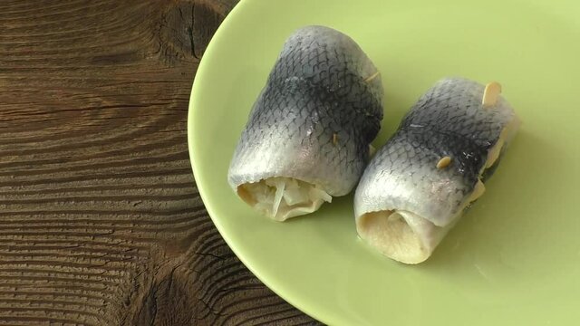 Fish rolls with sour herring on green plate
