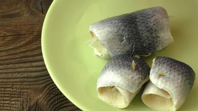 Fish rolls with sour herring on green plate
