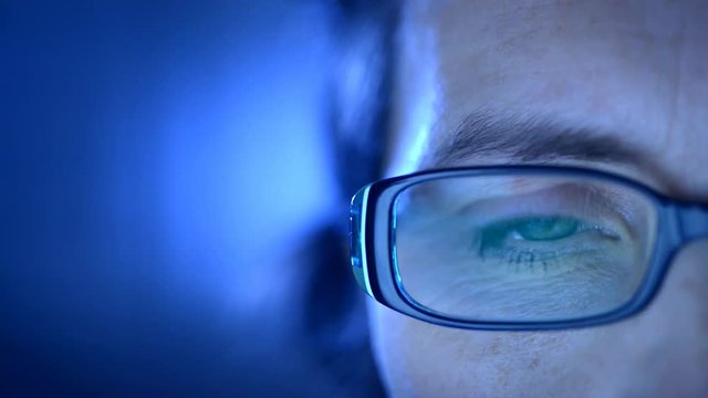 Closeup on one eye of a woman wearing glasses and looking at a computer screen.