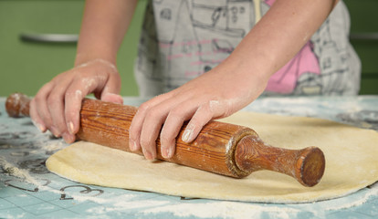 female hands in flour kneading dough on table