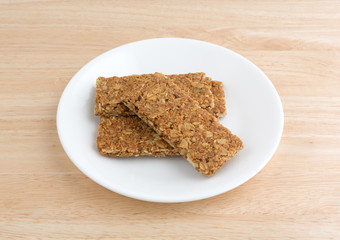 Cinnamon sesame and pumpkin seed granola bars on a plate side view on a wood table top.