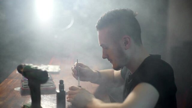 young man make a coil build on RDA in smoky vape shop