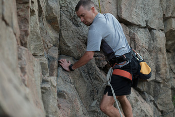 Male rock climber clings to a cliff