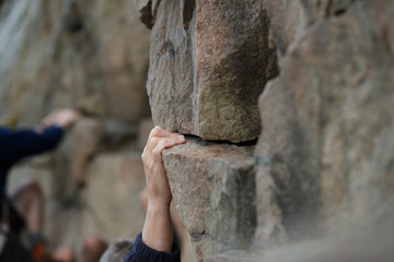 Hand of male rock climber clings to a cliff