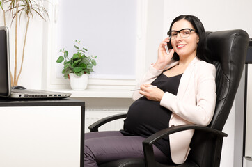 Pregnant woman talking on the phone in the office