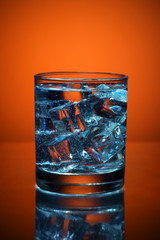 Close up of cold water glass with ice cubes.