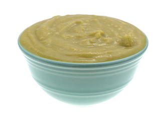 Bowl of green pea soup isolated on a white background side view.
