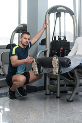 Fototapeta na wymiar Gym Coach Helping Youg Man On Legs