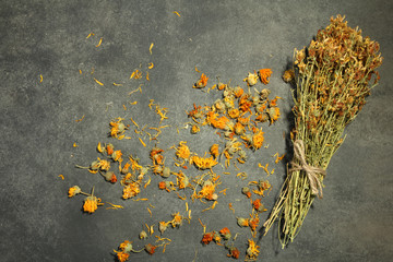 calendula dried flowers scattered on a dark background near the dried flowers tied up with rope - obrazy, fototapety, plakaty