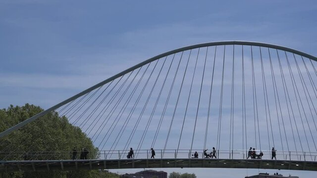 Bilbao - Bridge Zubizuri with pedestrians on a day with blue sky