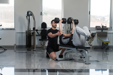 Fototapeta premium Gym Coach Helping Man On Chest Exercise