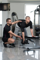 Fototapeta na wymiar Gym Coach Helping Man On Back Exercise