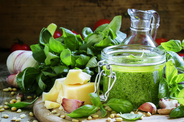 Pesto sauce in a glass jar, vintage wooden background, selective