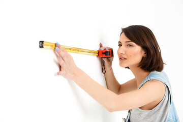portrait of young pretty girl, measuring the wall with tape