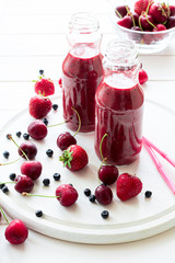 Two bottle of fresh strawberry blueberry smoothies on white wooden background. Selective focus
