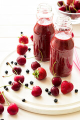Two bottle of fresh strawberry blueberry smoothies on white wooden background. Selective focus