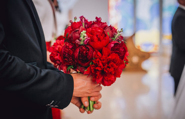 Bride Holding a Bouquet of red Peonies. Peonies on the white table.