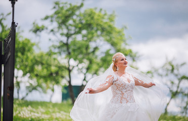 Fototapeta na wymiar Young beautiful bride plays a wedding dress. Dress develops in the wind. Happy bride in a wedding dress is spinning.