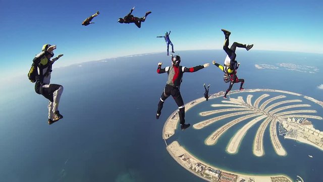 Professional skydivers parachuting above Dubai, make formation in sky. Sunny day. Extreme