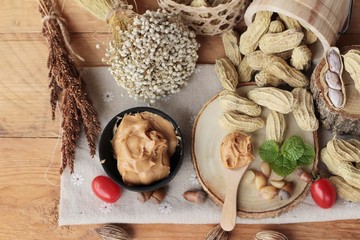 Peanut butter and peanut on wood background.