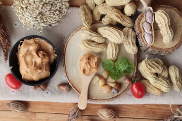 Peanut butter and peanut on wood background.